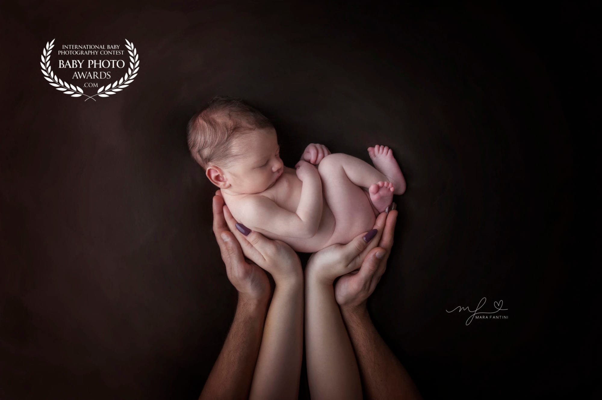 Fotografo neonato Roma - scatto premiato Baby Photo Awards | Mara Fantini Neonato addormentato tenuto tra le mani dei genitori, foto premiata a livello internazionale