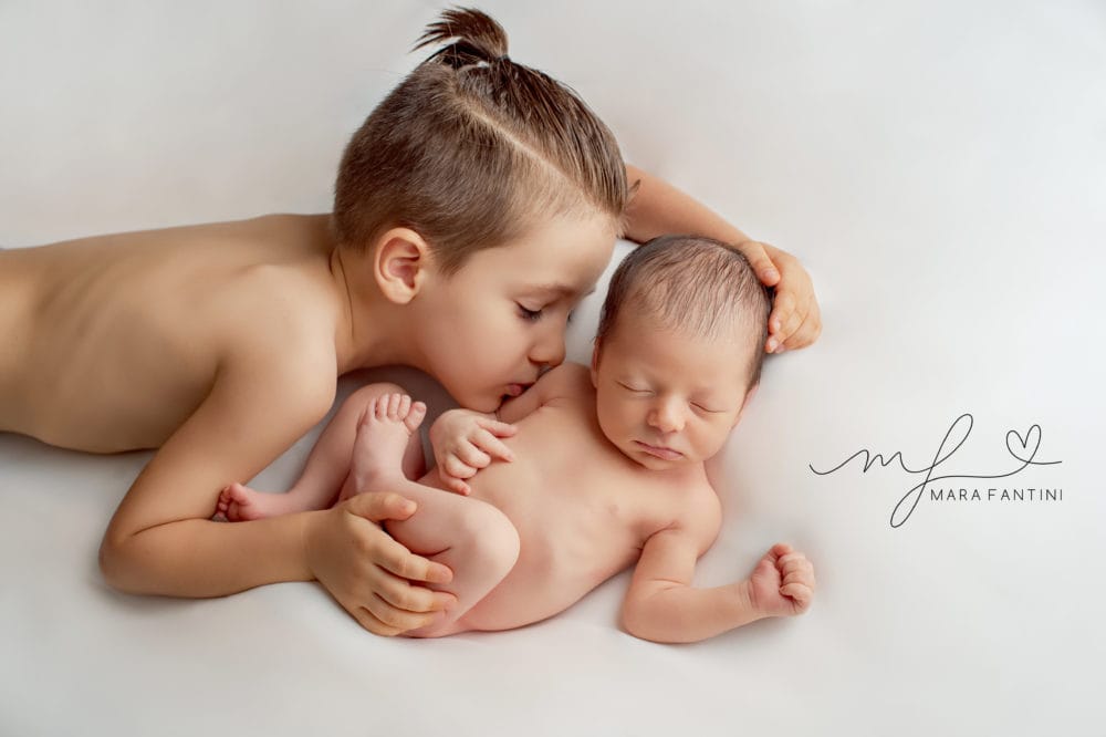 Foto neonato con fratellino - servizio in studio Roma | Mara Fantini Fratellino maggiore bacia il neonato appena nato durante il servizio fotografico in studio
