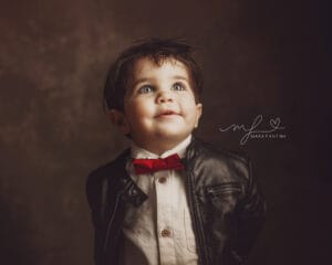 Bambino in giacca e papillon durante un servizio fotografico a Roma, sfondo scuro dal tocco pittorico, sguardo curioso e naturale