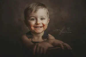 Bambino sorridente durante un servizio fotografico a Roma, sfondo scuro dal tocco pittorico, momento spontaneo e naturale