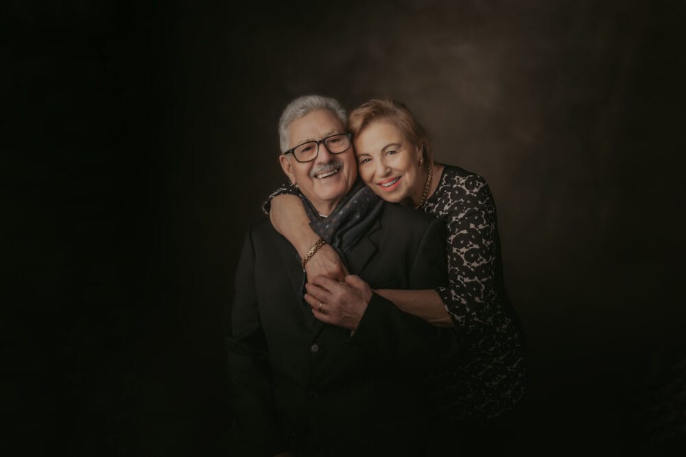 itratto-mamma-sorriso-servizio-fotografico-famiglia Madre sorridente abbracciata al marito durante un servizio fotografico di famiglia