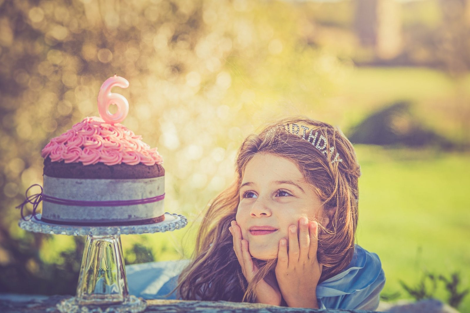 compleanno 6 anni parco acquedotti roma 02 Bambina appoggia il viso sulle mani con sguardo sognante verso la torta di compleanno, servizio fotografico di famiglia a Roma